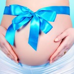 Close-up shot of a pregnant woman belly with big bow. Pregnancy. Healthcare. Studio shot.