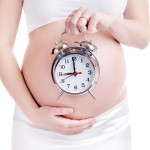 Pregnant woman belly with an alarm clock